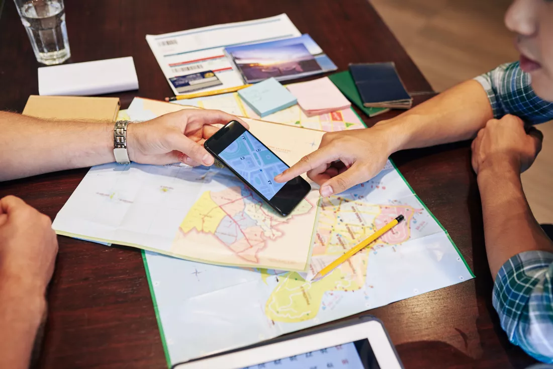 young-people-planning-trip-they-are-checking-paper-maps-online-application-smartphone