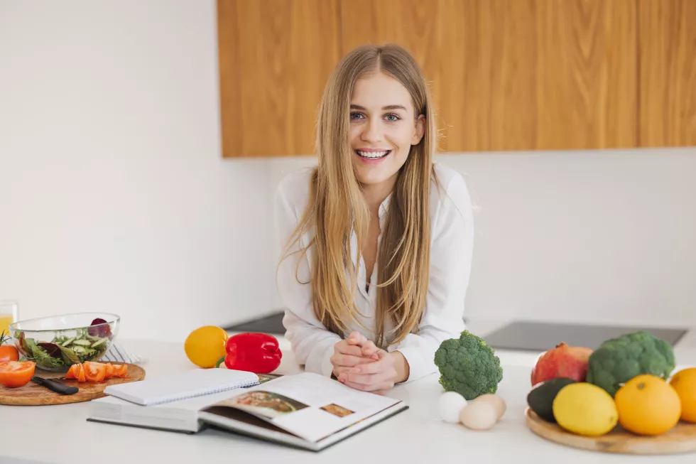 portrait-cute-blonde-girl-smiling-reading-recipe-book-kitchen
