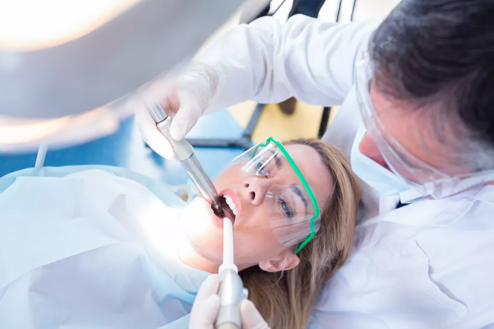 dentist-examining-his-patient-with-suction-hose