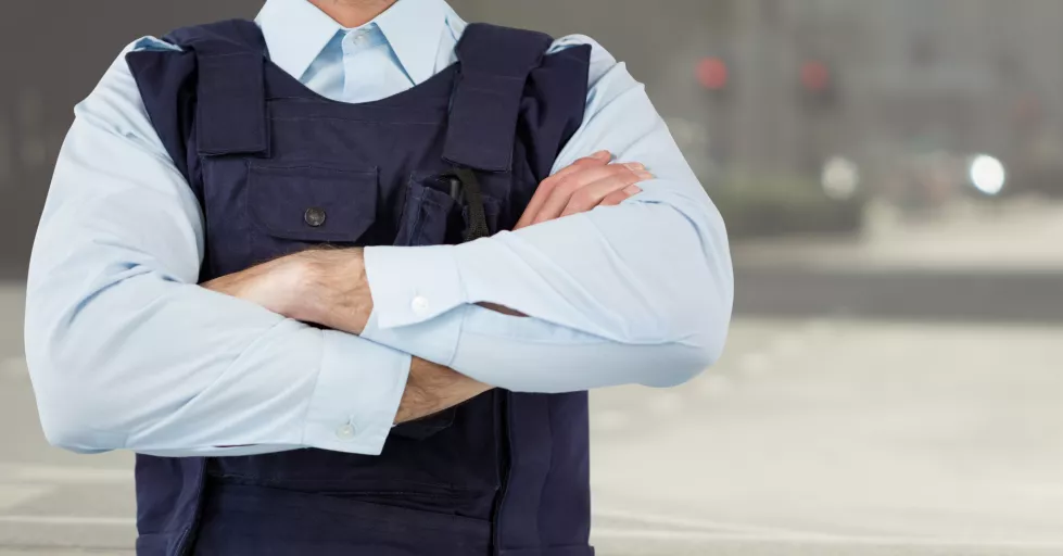 security-guard-mid-section-arms-folded-against-blurry-street