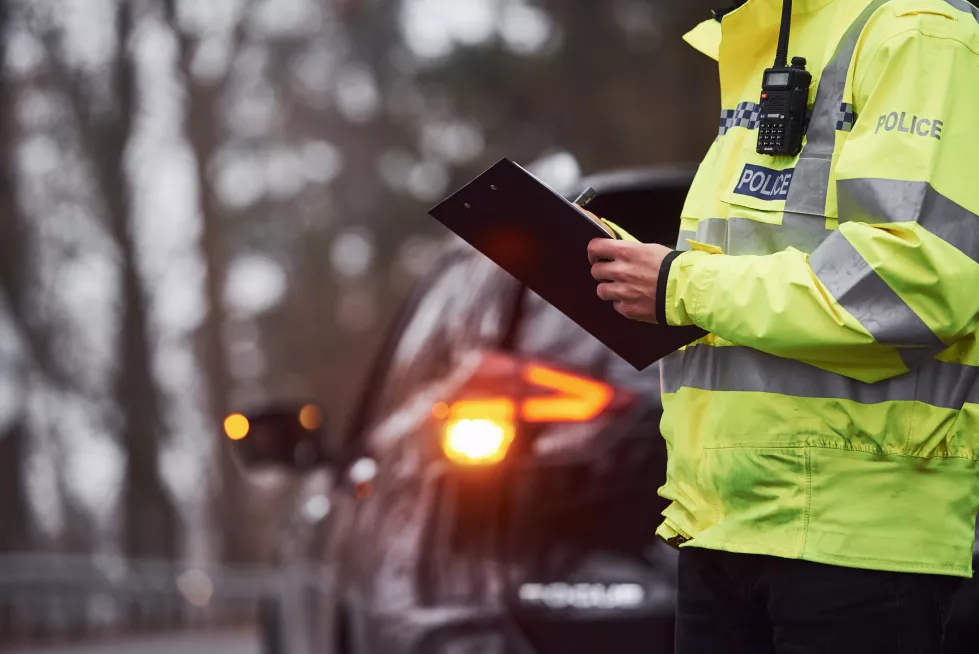 male-police-officer-green-uniform-standing-with-notepad-near-car(1)