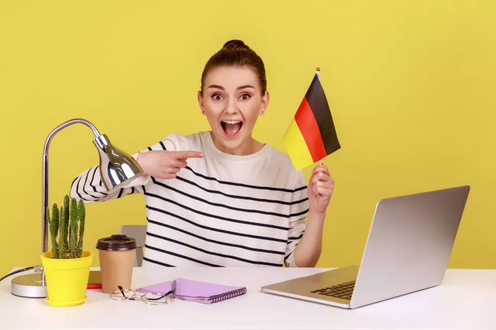 woman-office-employee-sitting-workplace-pointing-german-flag-job-education-abroad