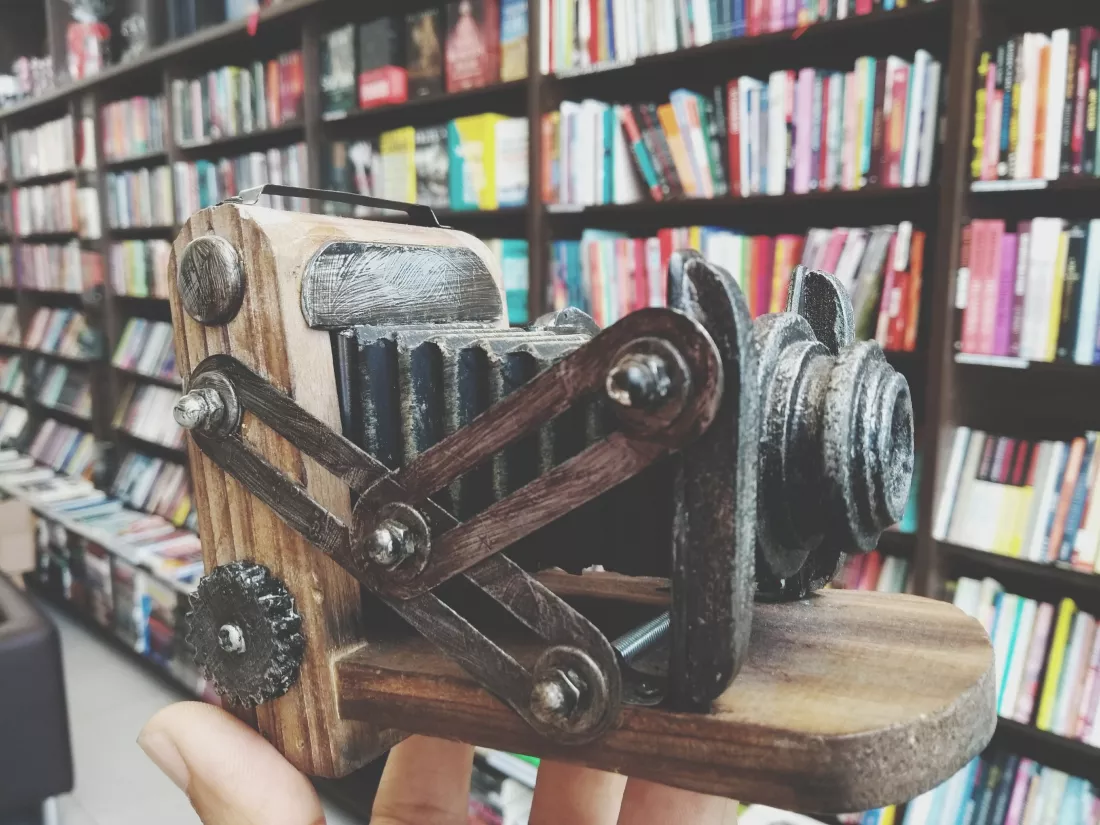cropped-hand-holding-souvenir-by-books-shelves