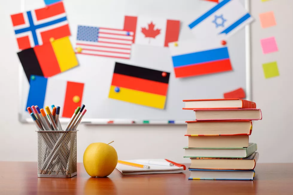stack-books-front-school-whiteboard-with-flags-different-countries