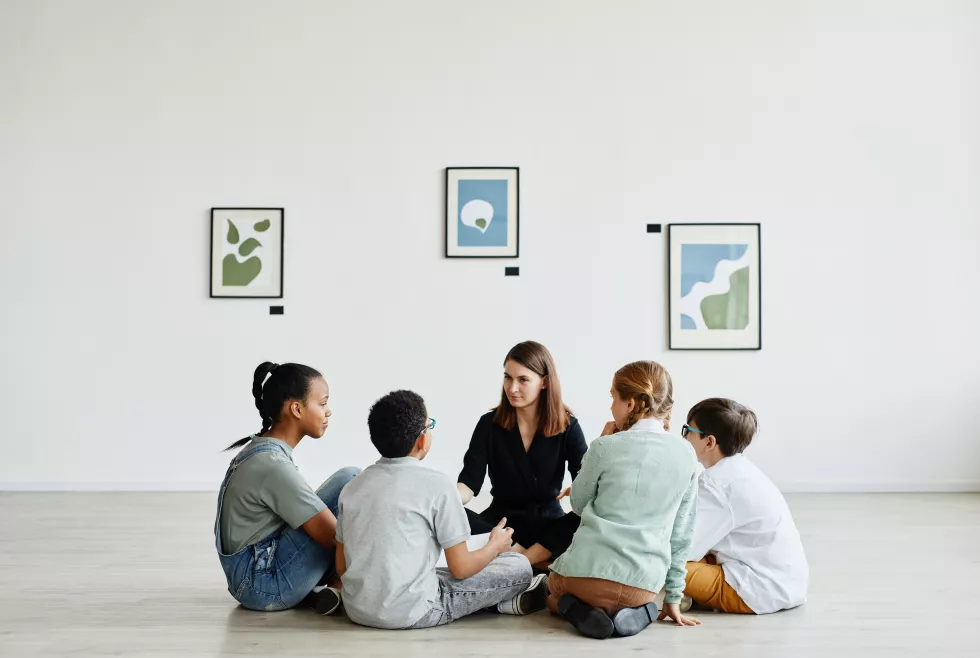 full-length-view-diverse-group-children-sitting-circle-class-art-gallery-copy-space(1)