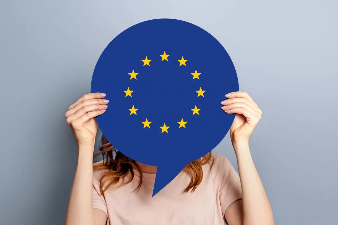 woman-holds-blank-white-speech-bubble-with-european-union-flag-isolated-grey-studio-background-news-information-channel-concept