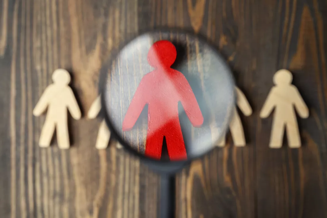 magnifying-glass-focuses-red-wooden-figure-from-crowd-wooden-figures