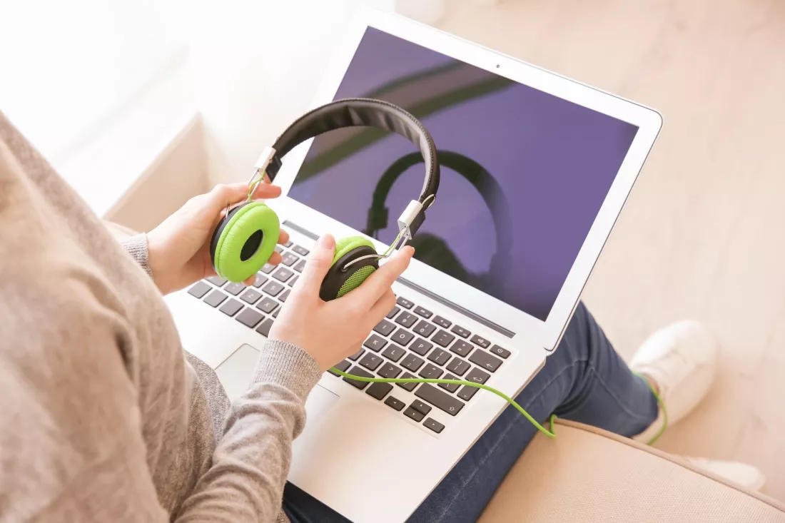audio-book-concept-young-woman-using-laptop-with-headphones-close-up