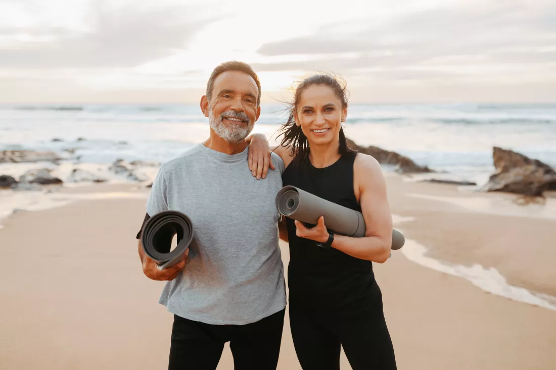 cheerful-senior-caucasian-lady-man-sportswear-with-mat-ready-workout-beach-morning