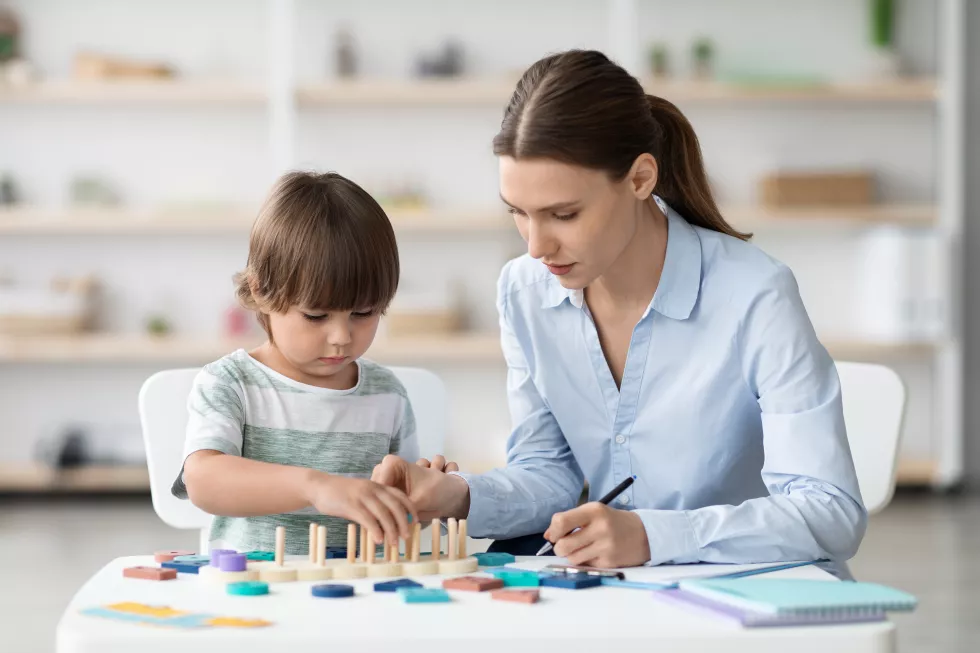 cute-little-boy-playing-logical-game-specialist-cabinet-woman-psychologist-making-notes-office