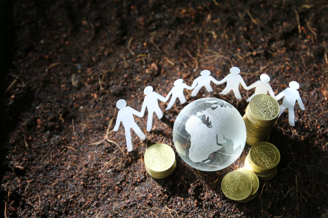 high-angle-view-paper-figurines-by-globe-with-coins-field