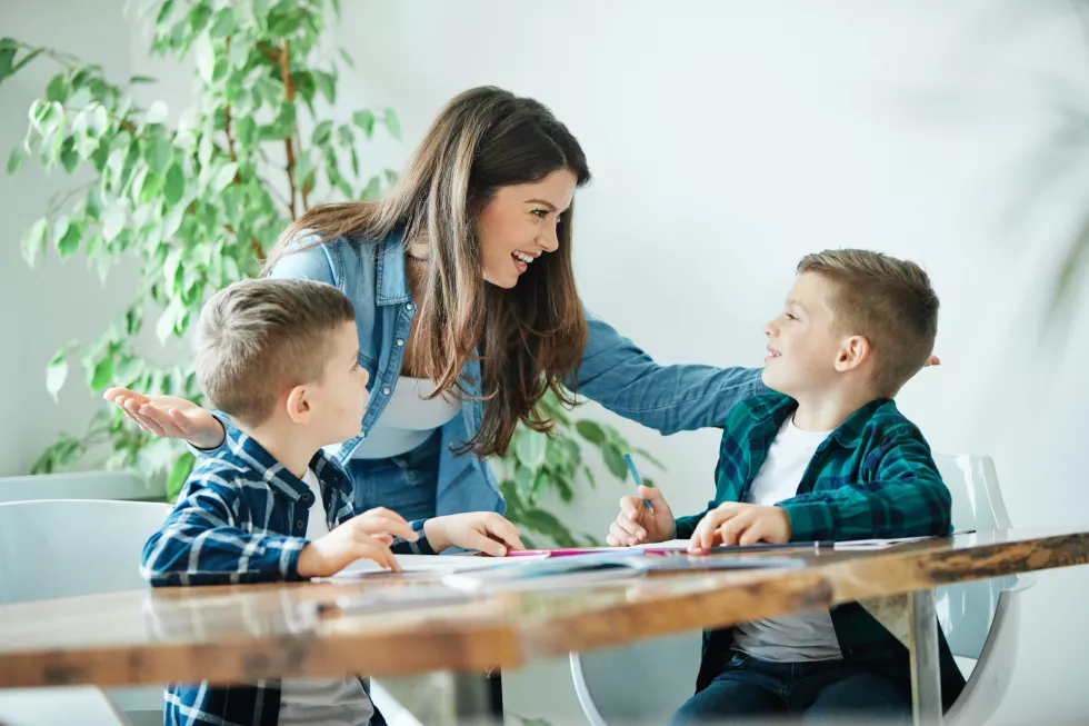 happy-mother-standing-by-cute-sons-studying-table