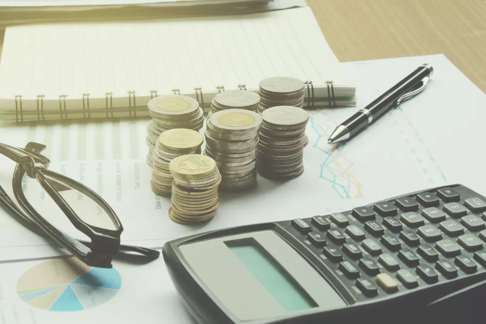close-up-calculator-with-coins-eyeglasses-table