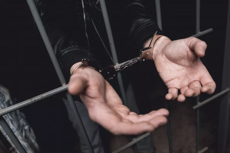 man-handcuffs-bars-police-station