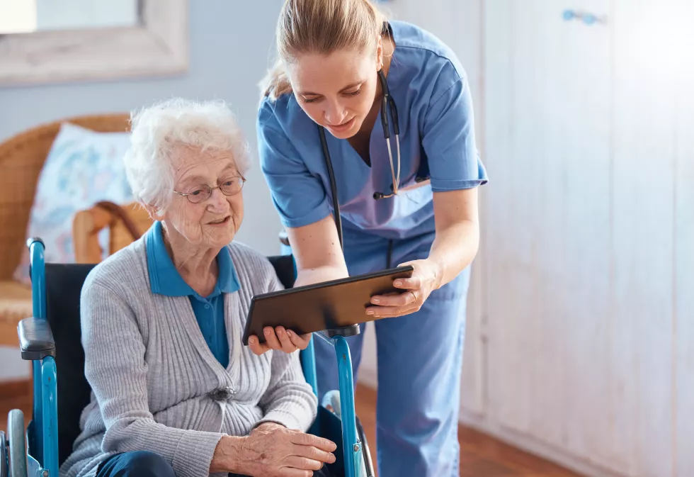 nursing-home-woman-doctor-with-tablet-checking-medical-results-chart-online-social-media-healthcare-tech-nurse-caregiver-help-consulting-with-elderly-patient-living-room-bedroom