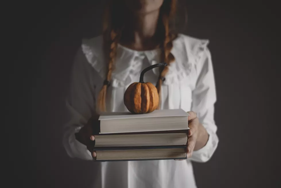 midsection-woman-holding-book-pumpkin