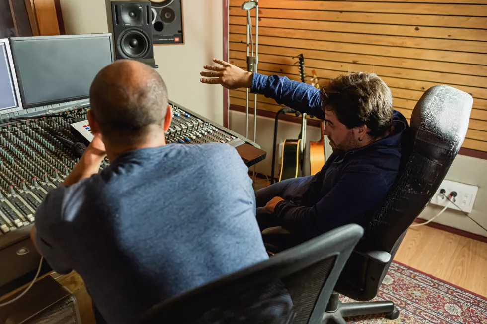 two-men-are-sitting-recording-studio-one-which-is-wearing-blue-jacket(1)
