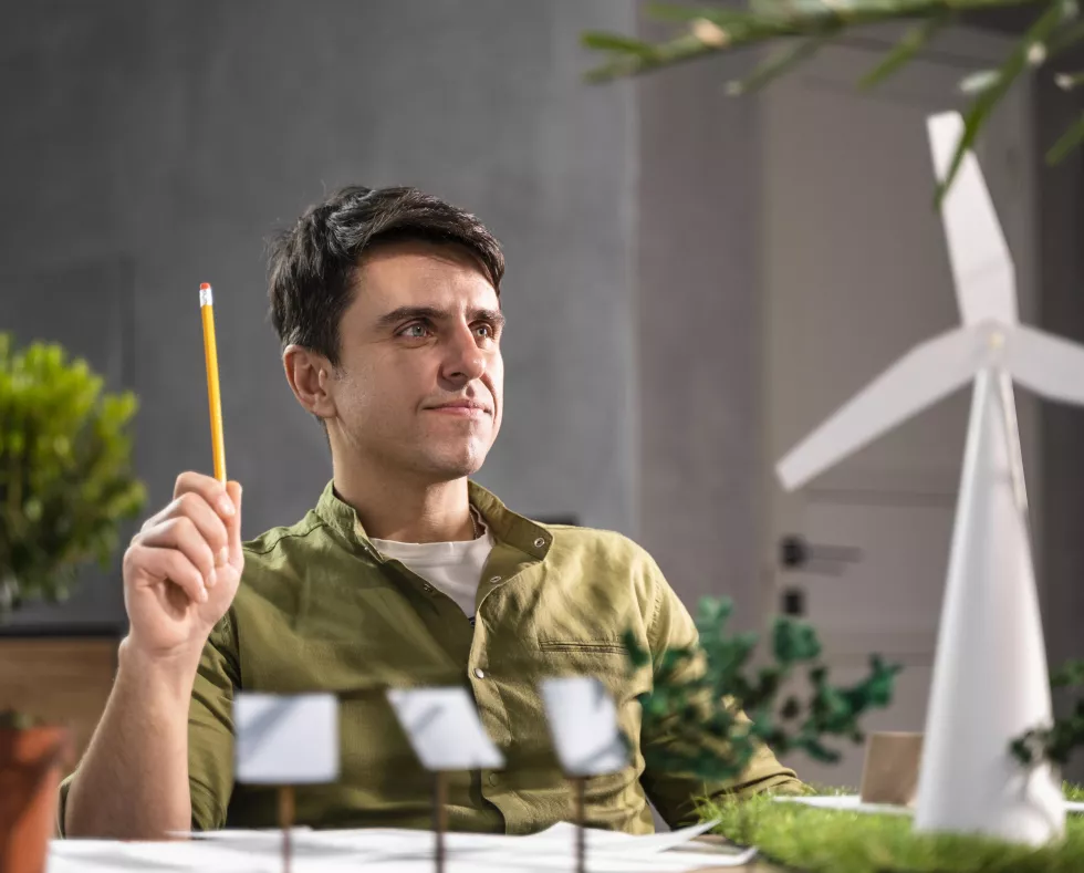 front-view-man-thinking-about-eco-friendly-wind-power-project-with-wind-turbines