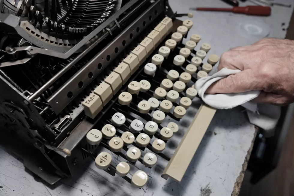 cropped-image-man-cleaning-typewriter-table