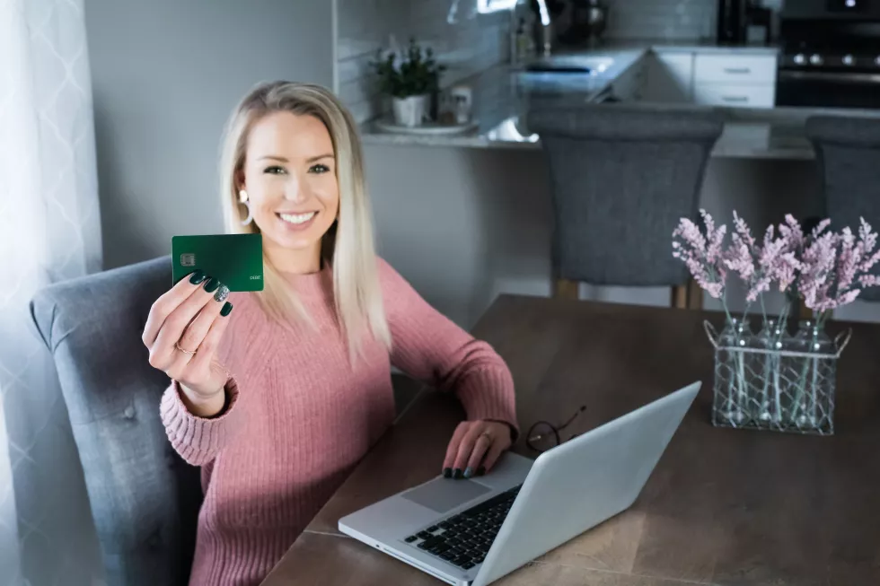 portrait-happy-young-woman-holding-credit-card-while-using-laptop-home
