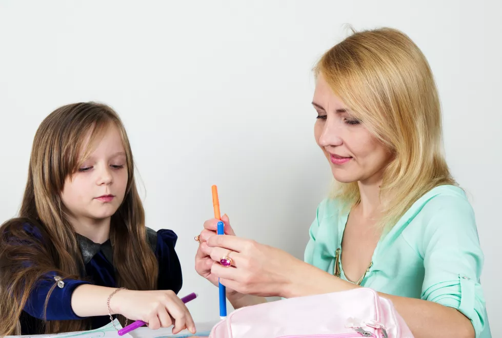 mother-daughter-holding-felt-tip-pens-against-white-background