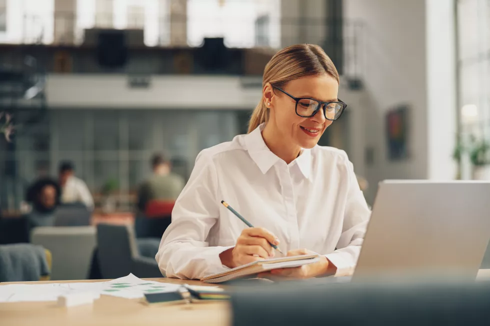 woman-office-worker-working-laptop-making-notes-while-sitting-coworking