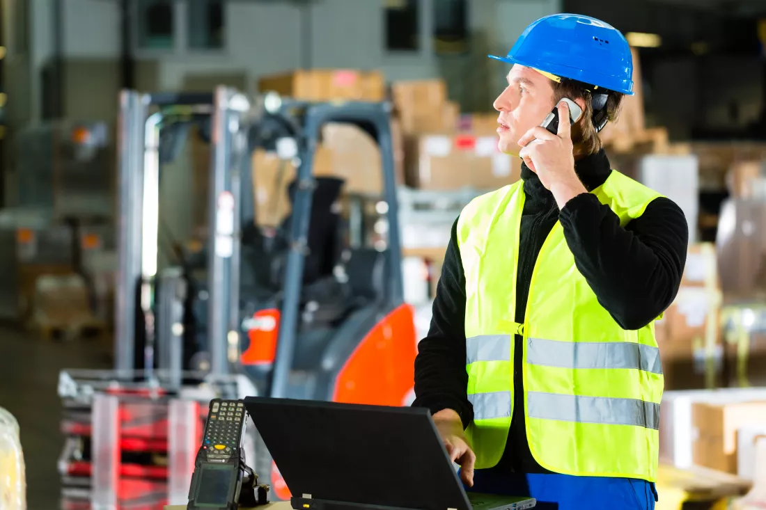 warehouseman-with-protective-vest-scanner-laptop-warehouse-freight-forwarding-company-using-mobile-phone