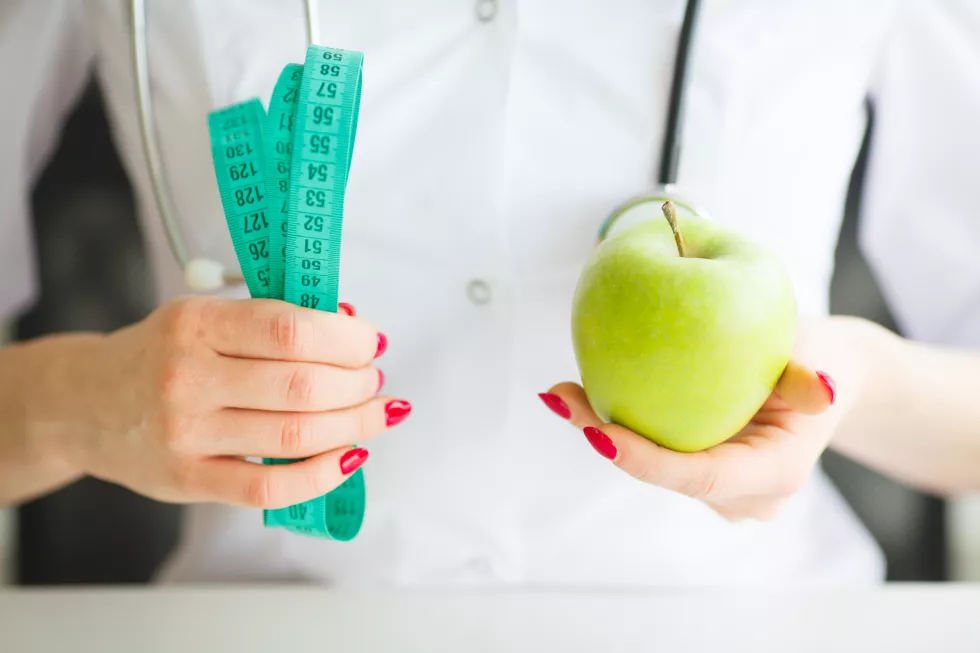 female-nutritionist-holding-apple-measure-tape
