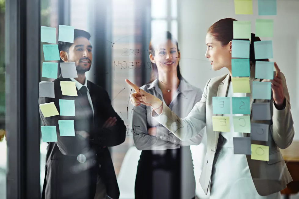 working-out-their-plan-as-team-shot-group-businesspeople-brainstorming-glass-wall-with-sticky-notes-office