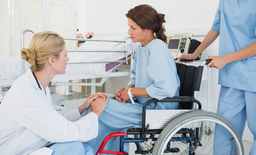 side-view-doctor-talking-female-patient-wheelchair-hospital