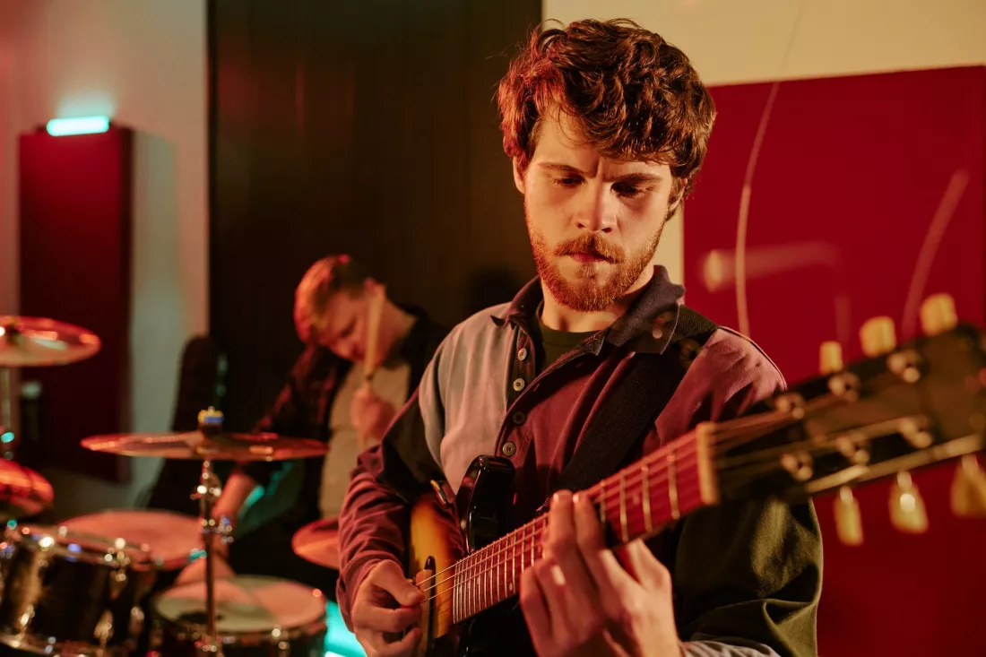 Młody gitarzysta gra podczas próby zespołu w studiu.