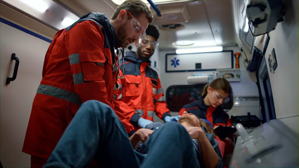 mixed-race-medical-team-giving-first-aid-help-ambulance-car-professional-paramedic-providing-medical-help-patient-medical-worker-checking-man-stomach-emergency-care-rescue-concept