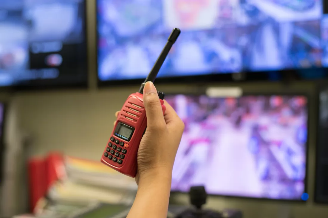 cropped-hand-woman-holding-walkie-talkie-against-computers
