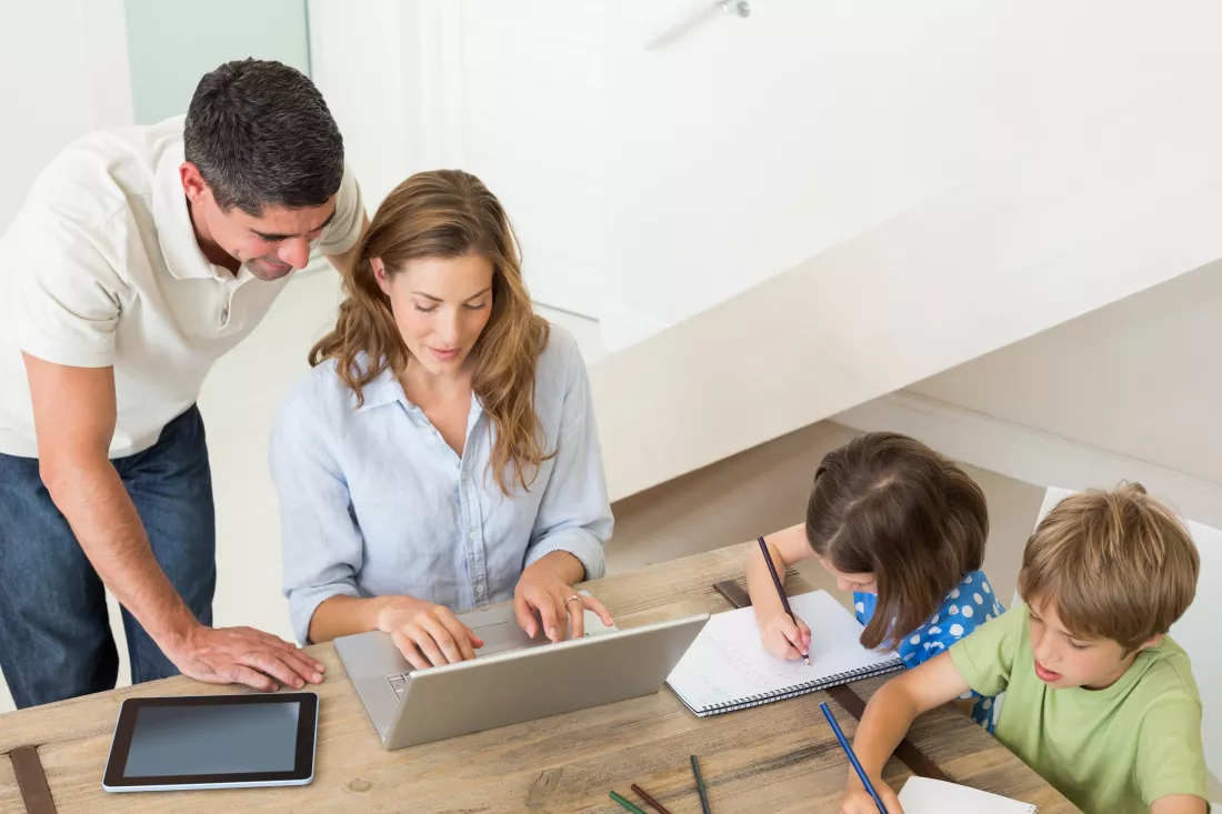 parents-using-laptop-while-children-coloring-home