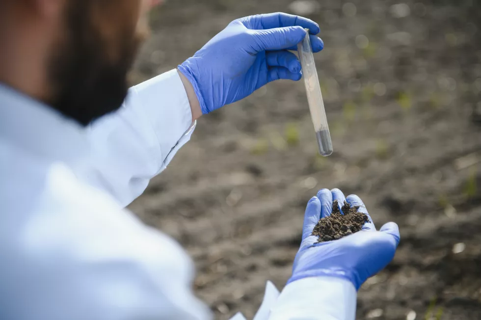 laboratory-worker-holding-professional-glassware-testing-black-soil-after-harvest-field