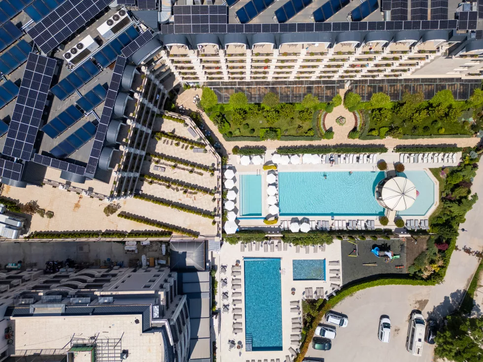 aerial-topdown-view-luxury-hotel-complex-with-solar-panels-swimming-pools-sunbeds-gardens-playground-modern-sustainable-resort-with-elegant-landscaping-amenities
