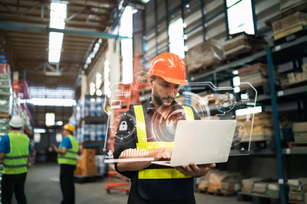professional-manager-man-employee-using-laptop-check-stock-working-warehouse-worker-wearing-high-visibility-clothing-hard-hat-helmet-checking-count-up-goods-boxes-delivery