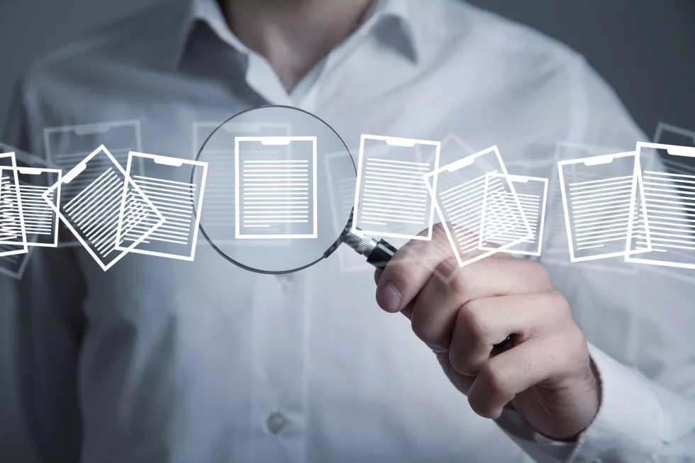 man-holding-magnifying-glass-with-documents