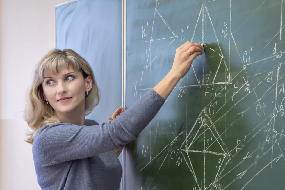 woman-teaching-while-standing-by-blackboard-classroom
