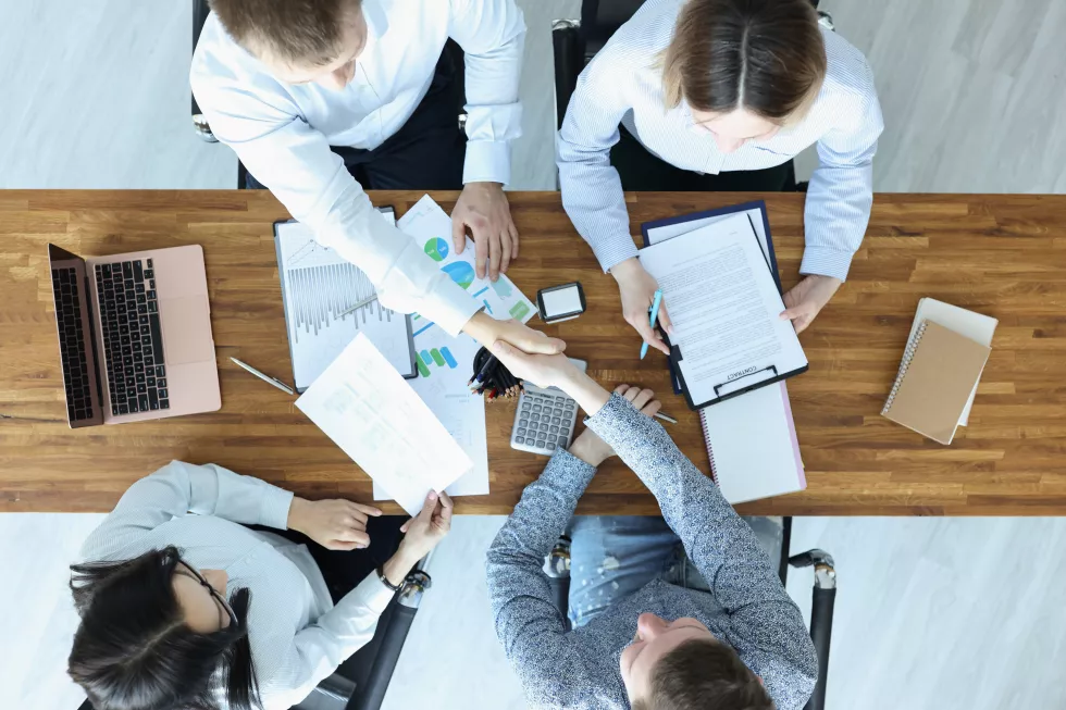group-people-sitting-table-shaking-hands-top-view-concluding-contracts-concept
