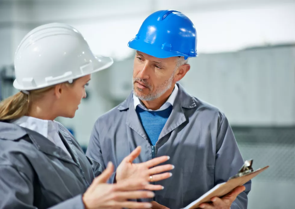 communication-takes-practice-two-factory-employees-wearing-hardhats-having-discussion