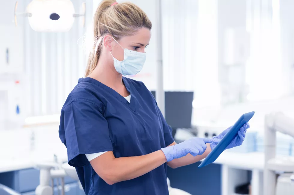 dentist-mask-blue-scrubs-using-her-tablet