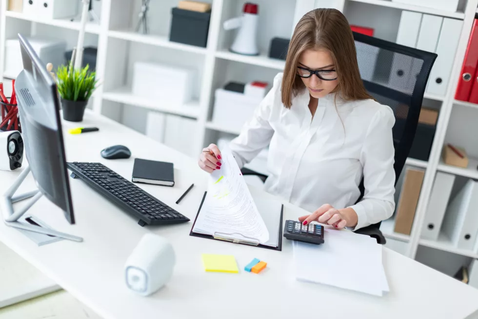 young-girl-sitting-table-working-with-computer-documents-calculator