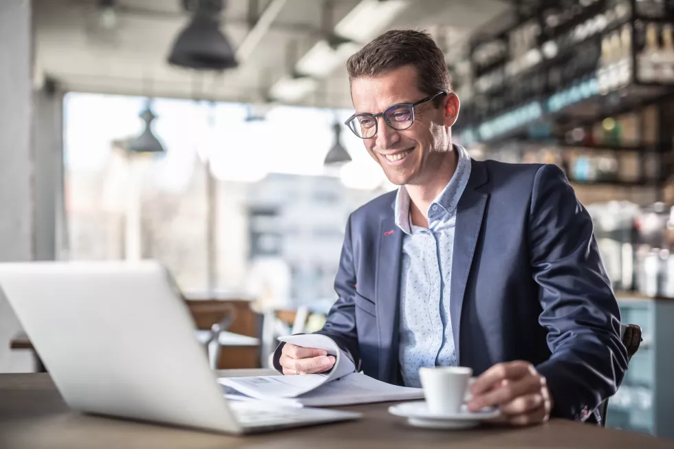 entrepreneur-smiles-computer-screen-while-having-coffee-business-break-vintage-restaurant