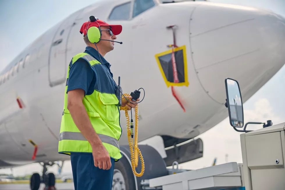 side-view-serious-airport-worker-sunglasses-headphones-staring-into-distance