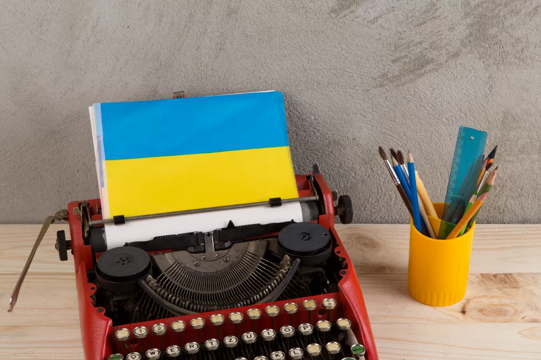 political-news-education-concept-red-typewriter-flag-ukraine-stationery-gray-cement-background