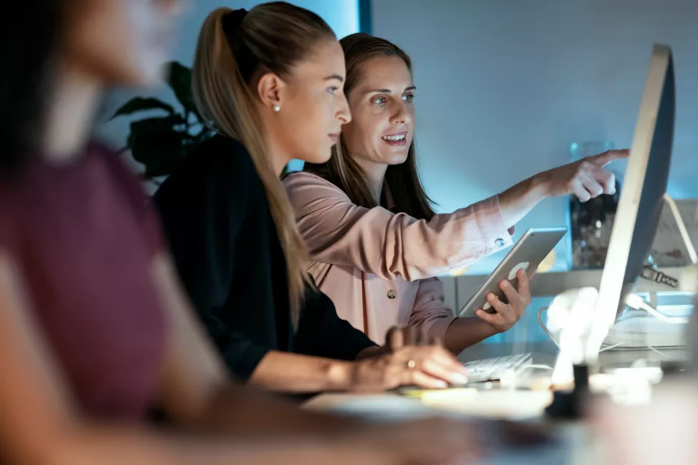 shot-two-smart-business-women-working-together-with-computer-digital-tablet-while-talking-office