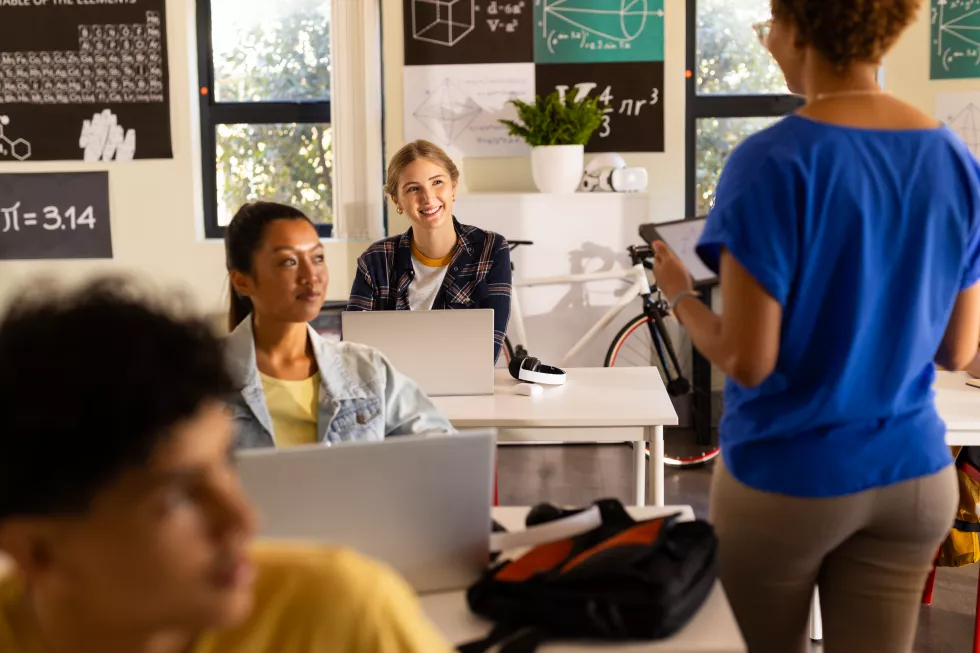 high-school-students-using-laptops-listening-teacher-classroom