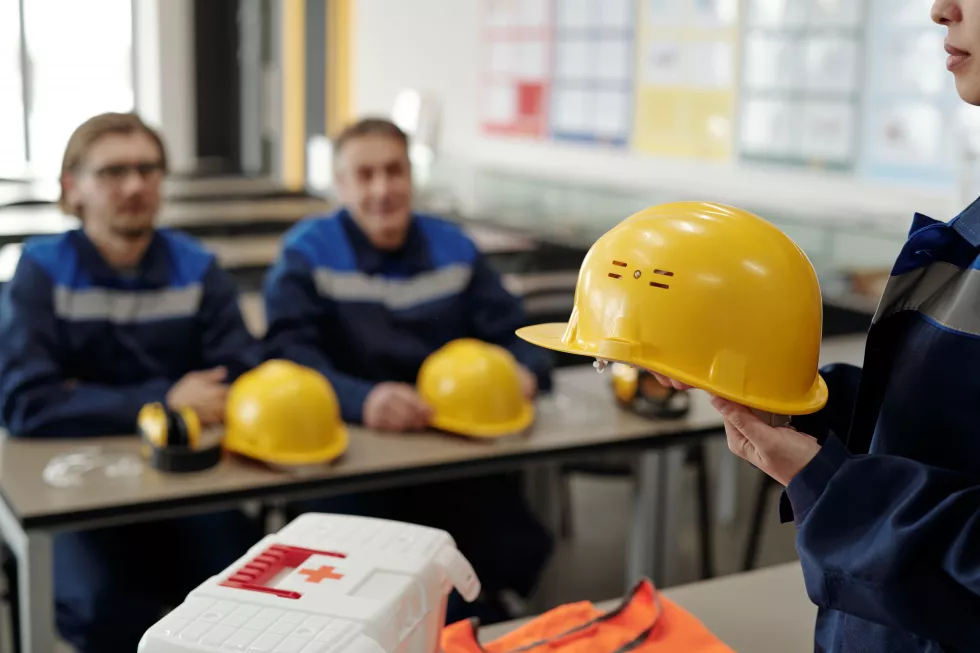 young-female-worker-uniform-holding-protective-helmet-while-standing-front-male-colleagues-lesson-basics-life-safety