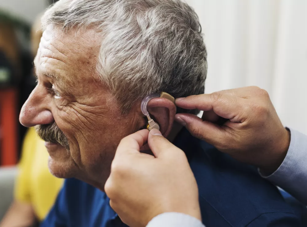 doctor-inserting-hearing-aid-patient-s-ear